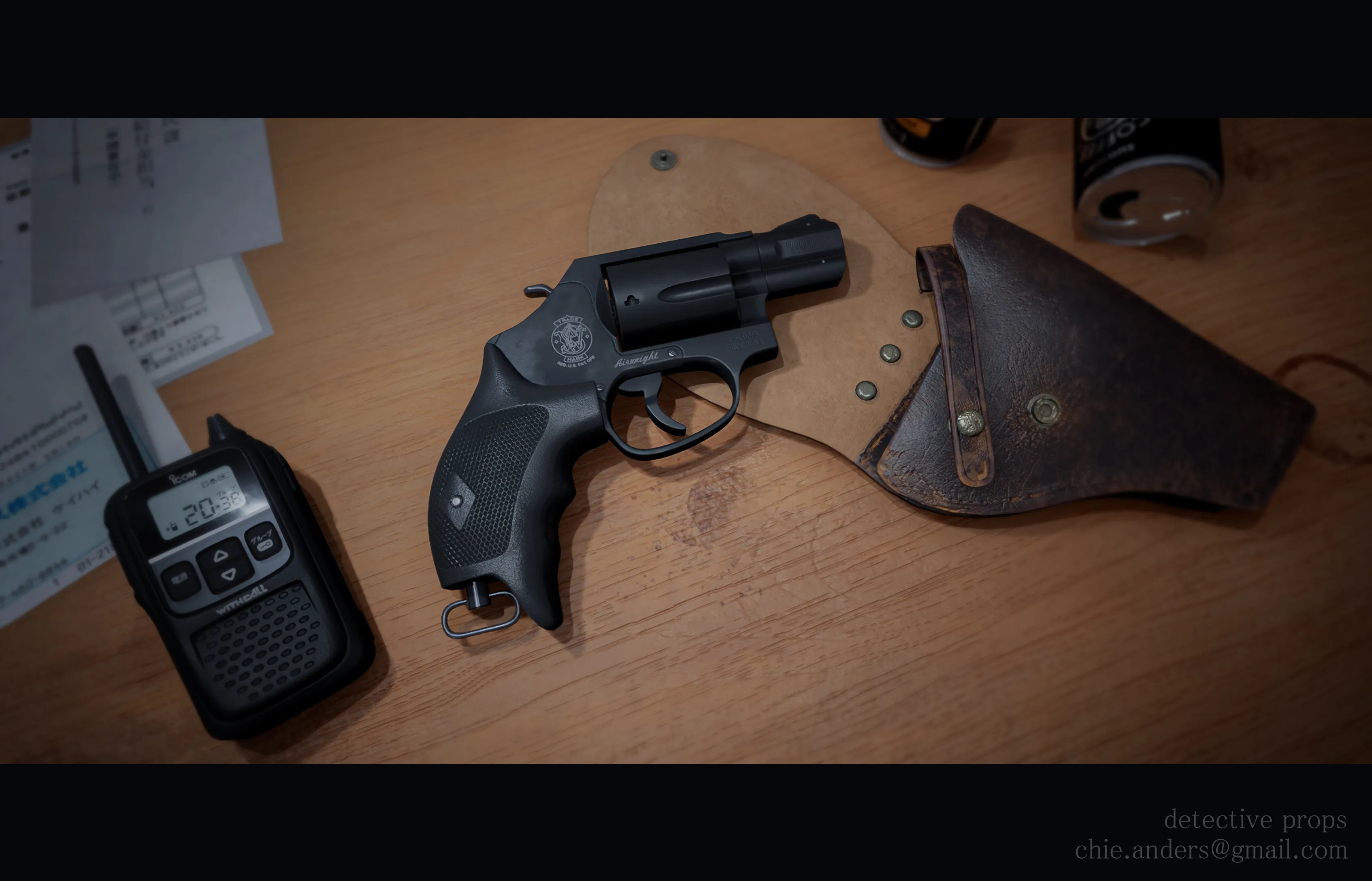 Detective's desk close up showing revolver, hoister, empty coffee cans, hand-held radio, and some papers